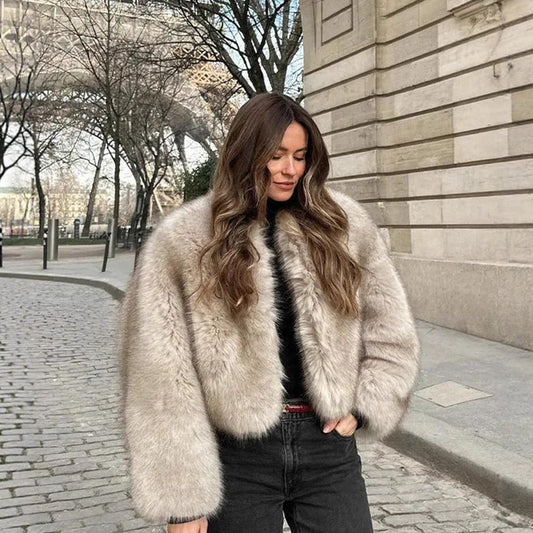 Woman wearing a fur coat standing on a city street.